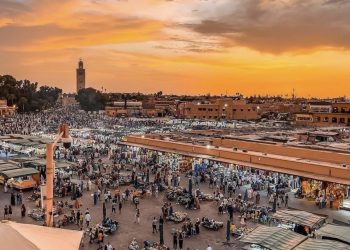 Jemaa el-Fnaa square in Marrakech with food stalls, performers, and vibrant crowds at sunset